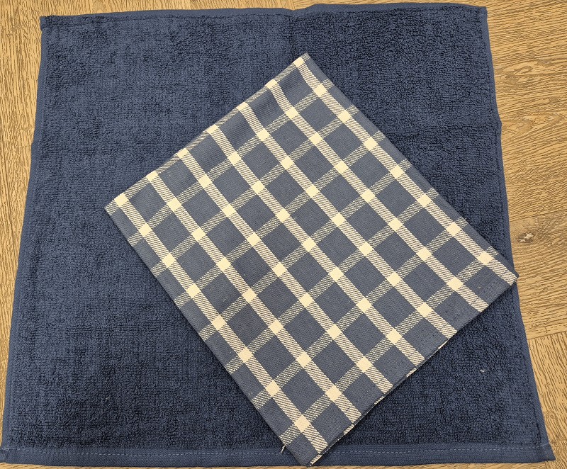 Handdoek en theedoek set. De handdoek is effen blauw en de theedoek geruit blauw.